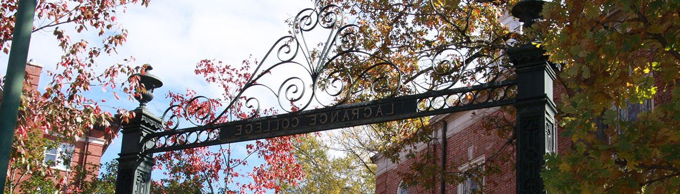 LaGrange College gateway with the sky, campus buildings, and fall leaved trees in the background.